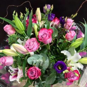 Margaret Raymond Florist Hand Tied Bouquet with bright pink roses and lilies, purple lisianthus, and twisted willow sticks